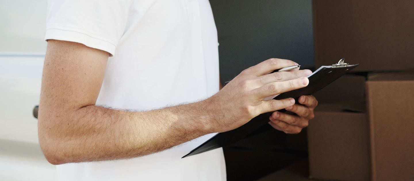 A man in a white shirt writing on a black clipboard.