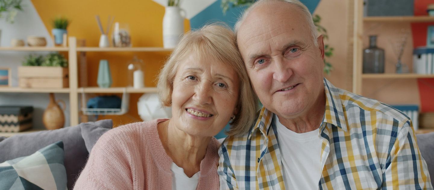 An older couple sitting together on a sofa at home.